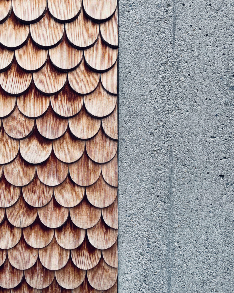 Ein Holzmuster für ein Dach und eine Wand neben einer Wand aus grobem Beton